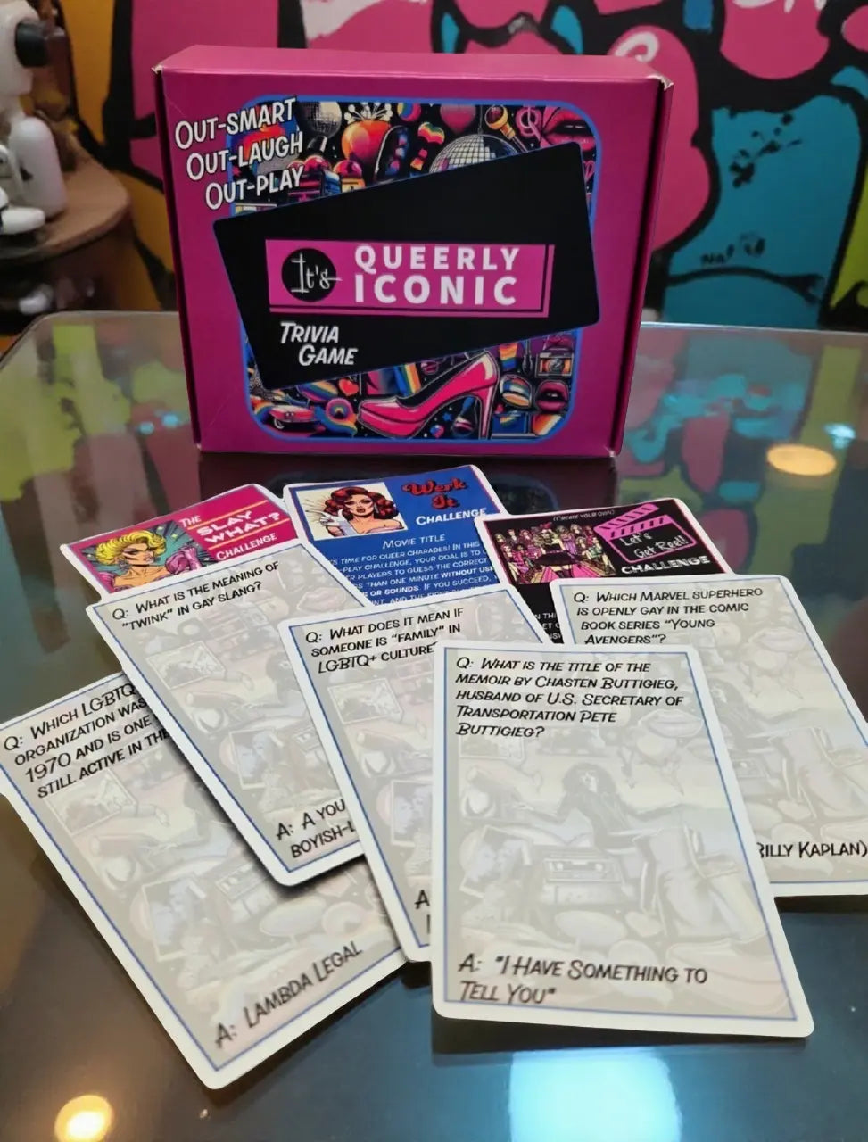 Queerly Iconic trivia game with cards on a reflective surface