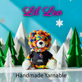 Colorful yarn bear with a black shirt in front of paper trees and mountains, branded 'Lil Leo'.